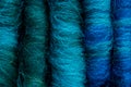 Close-up of five merino wool rolags, in shades ranging from greens to blues