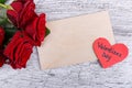 Close-up of five red roses on a gray background, with a paper heart and an envelope, the day of the holy Valentine. Royalty Free Stock Photo
