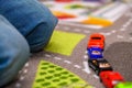 Close-up of five year old boy playing and lining up toy cars on a playing mat with roads
