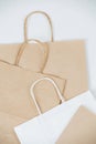 Close up of flat empty brown paper bags on a white surface with rope handles