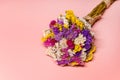 Close up flat lay photo of a beautiful colorful bunch of dried everlasting flowers on a pink background