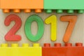 Close up of 2017 flat plastics numbers with plastic toy blocks framing on wooden background