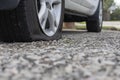 Close up of flat rear tire of white suv track car vehicle automobile punctured by nail. Summer day, residential street. Royalty Free Stock Photo