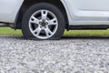 Close up of flat rear tire of white suv track car vehicle automobile punctured by nail. Summer day, residential street. Royalty Free Stock Photo