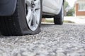 Close up of flat rear tire of white suv track car vehicle automobile punctured by nail. Summer day, residential street.