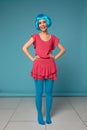 Close up of a flirtatious female model on blue background wearing a blue wig. Pretty glamorous woman pink hair charm