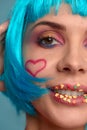 Close up of a flirtatious female model on blue background wearing a blue wig. Pretty glamorous woman pink hair charm