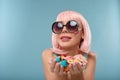 Close up of a flirtatious female model on blue background wearing a pink wig holding different kinds of candies. Pretty