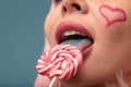 Close up of a flirtatious female model with a candy in mouth. Pretty glamorous woman pink hair charm sweets lifestyle