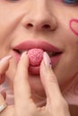 Close up of a flirtatious female model with a candy in mouth. Pretty glamorous woman pink hair charm sweets lifestyle