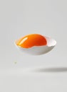 Close-up of a floating white eggshell with vibrant orange yolk and dripping egg white Royalty Free Stock Photo
