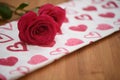 Close up flower photography image of fresh red roses on a red and white love heart pattern cloth for Valentines Day