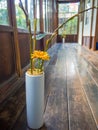 Close up of a flower vase with a yellow flower at indoor view of hall with a wooden floor, in Kyoto, Japan