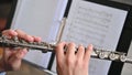 Close-up of flutist playing the clarinet against the background of a sheet music.