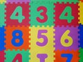 Close up of Foam colorful puzzle pieces. Children`s play rubber floor background. Texture of colored rubber number blocks for