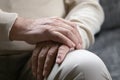 Close up focus on male wrinkled hands folded on lap.