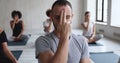 Male yogi couch and group of multiethnic people meditating indoors