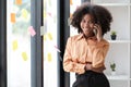 African American female employee write down on colorful sticky notes manage list, concentrated biracial woman work on