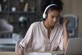 Close up focused African American woman in headphones taking notes Royalty Free Stock Photo