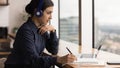 Close up focused Indian woman wearing headphones taking notes Royalty Free Stock Photo