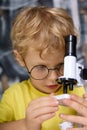 In the hands of a bespectacled boy a real microscope with a tube of black color Royalty Free Stock Photo