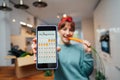 Close up focused phone with active online mobile app of Veganuary diet calendar in woman's hand, who is eating fresh