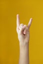 folded fingers in shape of goat with two fingers raised up of teen hand on yellow background. Royalty Free Stock Photo