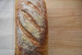 Close up food image of a fresh home made artisan white bread loaf on a cream cloth and wood board background