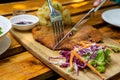 Close Up Food Photo of Knive and Fork being used to cut a Chicken Schnitzel on a Wooden Board with Homemade Potato Salad and