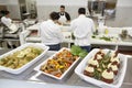 Close-up of foodstuff in serving dishes with chefs working in kitchen