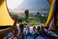 Close up foot of group of friends relax lying down and cross leg on blanket in tent and looking at mountain view in sunrise time