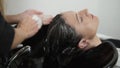 Close up footage of washing head of woman with long, dark hair with shampoo. Massaging the head sculp. Close up hands of