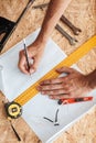 Close up foreman hands holding pencil and measuring tape on paper in workshop isolated