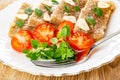 Close up of fork in plate with pieces of meat jelly, slices of garlic, basil, tomato on wooden table