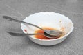 Close-up fork and spoon lie in a white dirty plate, gray background, copy space. Dirty dishes after dinner Royalty Free Stock Photo