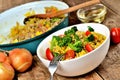 Close-up of fork and tuna risotto with vegetables, tomatoes, broccoli and parsley in the bowl, onions, oil and pan in Royalty Free Stock Photo