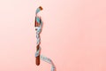 Close up of fork wrapped in measuring tape on pink background. Overweight and overeating concept