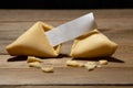 Close up of fortune cookie with blank paper inside and cookie crumbles on a bamboo board