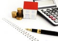 Close up of Fountain pen and paper house and coin stack and calculator background