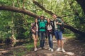 Close up of four cheerful friends in the summer nice wood. They are hikers, walking and picking place for camping, embracing, pos