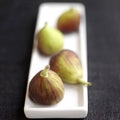 Close up of four figs on a small plate. Conceptual image
