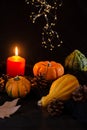 Close-up of four green and orange pumpkins, with autumn leaves and burning orange candle, selective focus, on dark wooden table Royalty Free Stock Photo