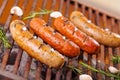 Close up of four grilling sausages on barbecue grill with some species. BBQ in the garden. Bavarian sausages Royalty Free Stock Photo