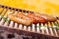 Close up of four grilling sausages on barbecue grill with some species. BBQ in the garden. Bavarian sausages Royalty Free Stock Photo