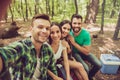 Close up of four happy friends tourists in the spring nice wood, embracing, posing for a selfie shot, that handsome blond guy is