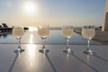 Close up of four ouzo stemmed glasses on a white stand during sunset