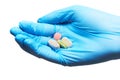 Close up of four white, pink and green tablets on female doctor's hand in blue sterilized surgical glove