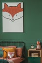 Close-up of a fox painting on a green wall above an orange and black bed for a child in a bedroom interior with plush fox toys.