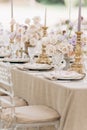 Close-up of fragment of wedding table in beige tones of with bouquets of roses, candlesticks.