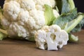 Raw cauliflower head and floret on wooden board